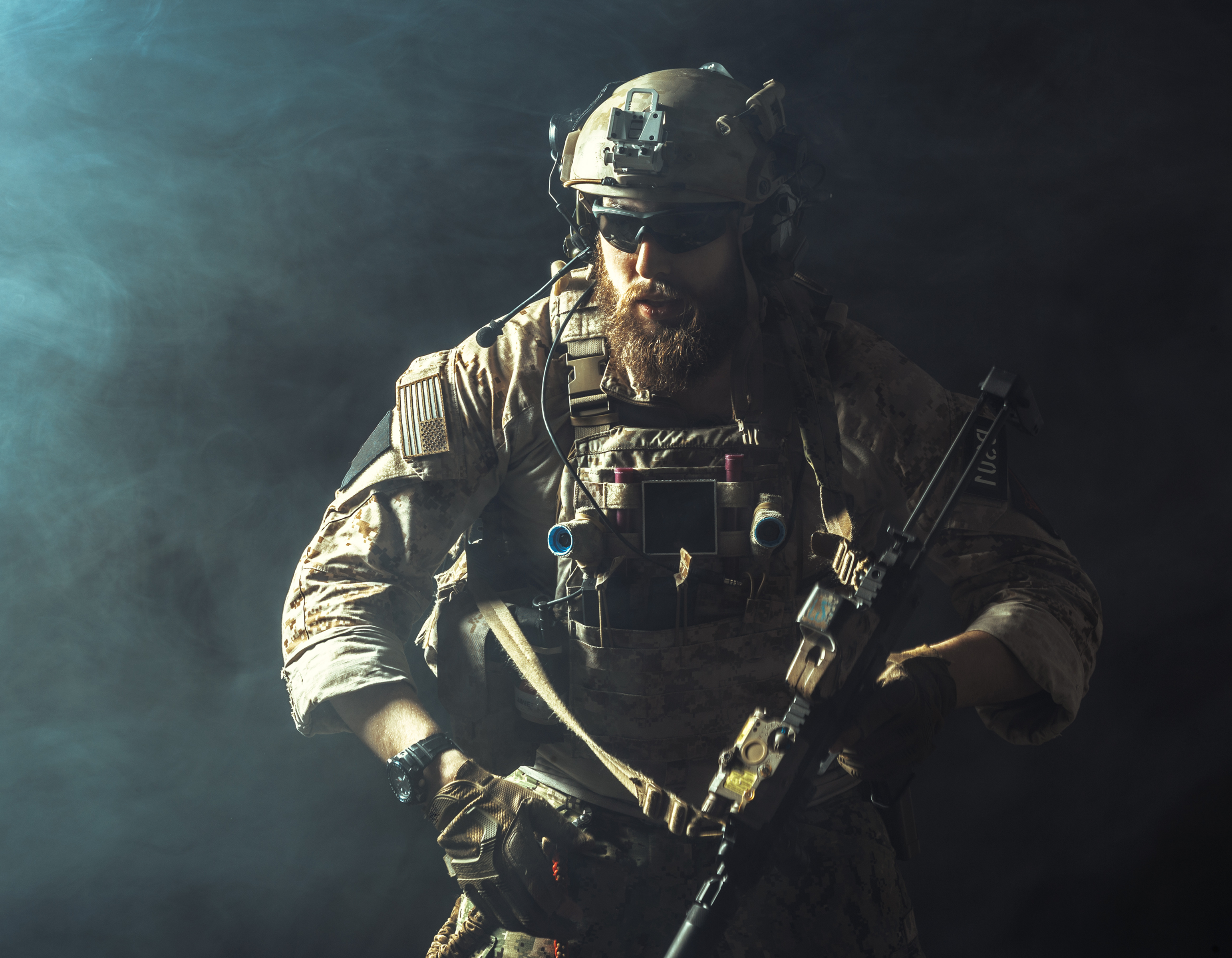 A soldier equipped with tactical gear, including a helmet, communication headset, utility vest, and weapon, standing ready in a dramatic, smoke-filled environment